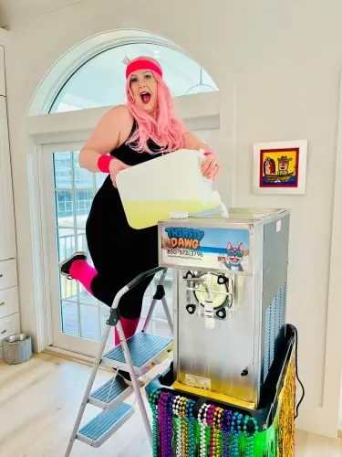 Woman in costume pouring mix into a frozen drink machine for a Mardi Gras party rental in Pensacola
