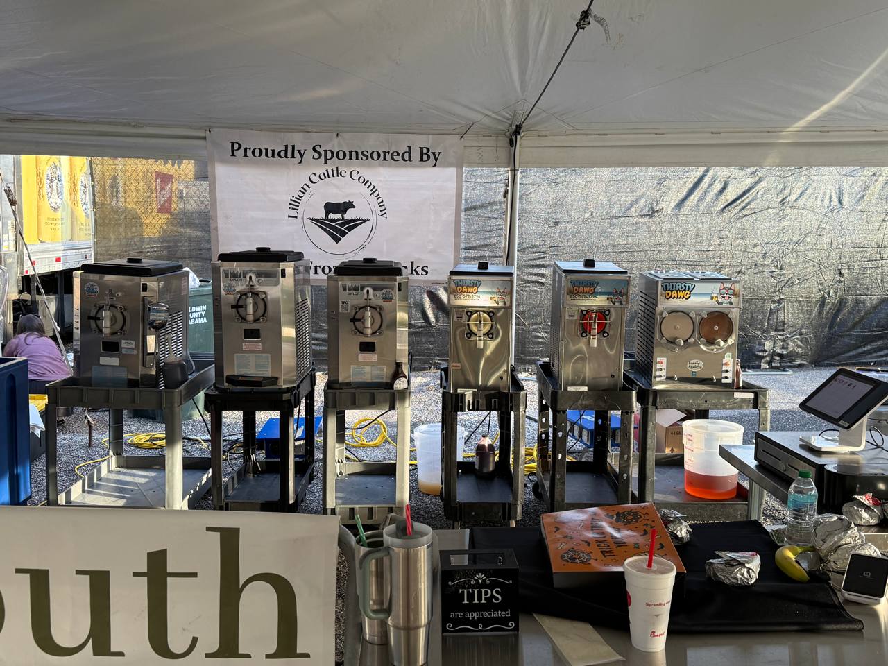Stainless steel frozen drink machines set up outdoors under a tent
